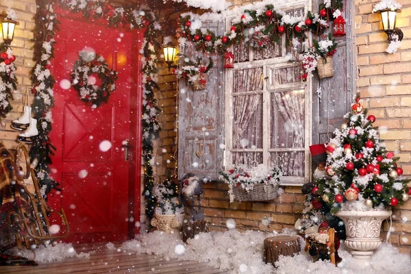 Christmas decor on a patio. Doors are decorated by a festive chaplet and toys. Fir-tree at a window