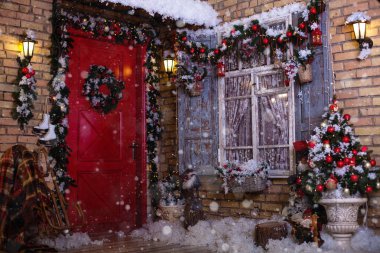 Bir veranda üzerinde Noel dekor. Kapılar şenlikli bir çelenk ve oyuncaklar tarafından dekore edilmiştir. Bir pencere, köknar ağacı