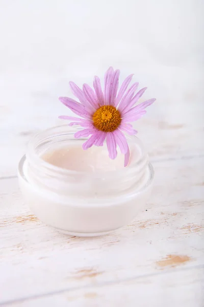 Crema facial y flor sobre un fondo blanco de madera. cosmética orgánica natural facial . —  Fotos de Stock