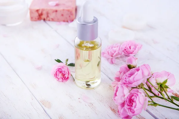 Ajuste de spa con olla de crema hidratante hermosas rosas rosadas y aceite de rosa sobre fondo blanco vista superior —  Fotos de Stock