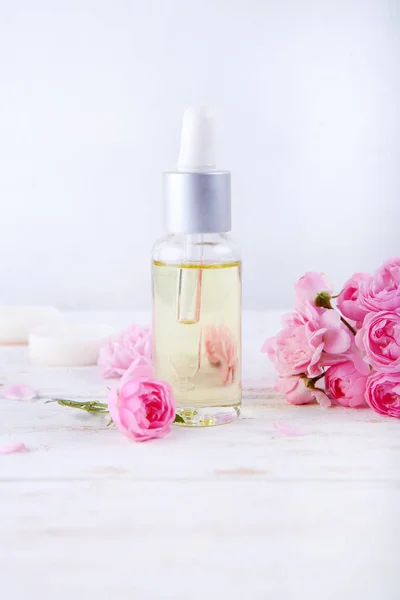 Spa pengaturan dengan pot pelembab krim indah mawar merah muda dan minyak mawar di latar belakang putih — Stok Foto