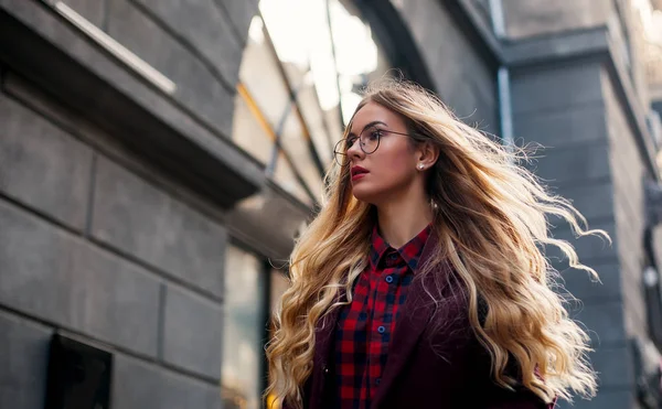 Begreppet gatumode. Ung vacker modell i staden. Vacker blond kvinna bär solglasögon. Hår fladdrar i vinden. — Stockfoto