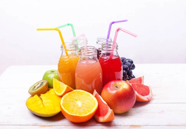 Satır taze meyve suları Smoothie beş şişe kırmızı yeşil pembe bordo sarı renk meyveler kavun elma kivi üzüm turuncu Mango nar tropikal seçici odak Beyaz ahşap masa.