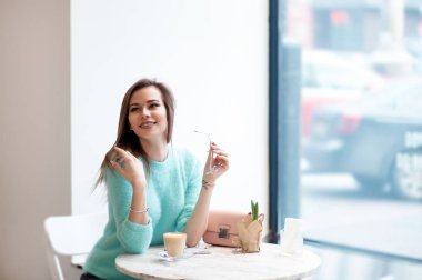 Yakışıklı genç kadın whith gözlük kafede seyir uzak tutan telefon chillling süre.