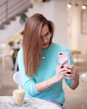 genç güzel kız resimleri sosyal ağlar için bir telefon ile bir kafede alıyor