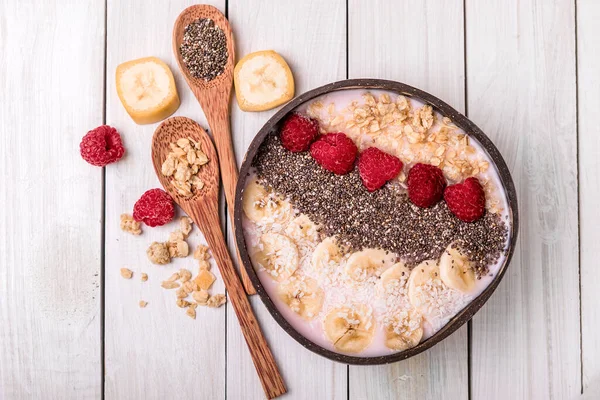 Hindistan cevizi kasesinde granola ile smoothie kasesi, üst manzara. Sağlıklı vejetaryen gıda konsepti. Bitki temelli diyet kavramı