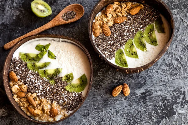Sağlıklı vejetaryen kahvaltısı. Chia tohumları, bir dilim kivi, granola ve hindistan cevizi tabağında fındık..