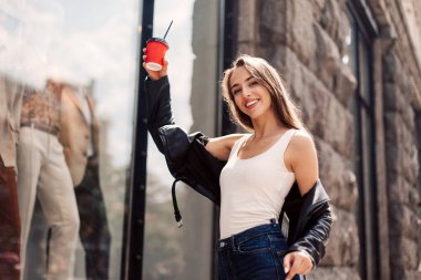 Yakından çekilen komik, neşeli, çekici genç kadınlar eğleniyor, gülümsüyor. Şık giyinmiş bir kız. Gülümseyen ve kahve içen butik kızın penceresine poz vermek.