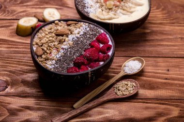 Ahududu ve chia tohumları üzerine donmuş böğürtlen ve granola konmuş meyve suyu kaseleri. Doğal hindistan cevizli sağlıklı besin. Sağlıklı vegan gıda kavramı..