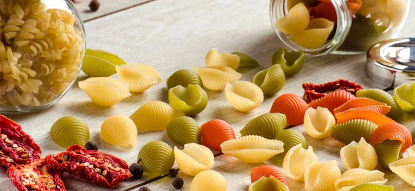 Pasta shells, scattered cans and sun-dried tomatoes on the table — Stock Photo, Image