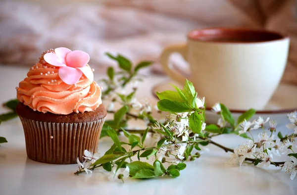 Cap-pastel en un plato y flores de cerezo rama — Foto de Stock