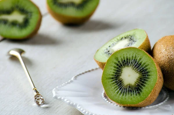 Fructele kiwi pe o farfurie albă și lingură de desert — Fotografie, imagine de stoc