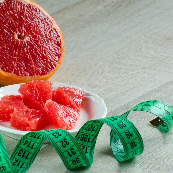 Dilim greyfurt ve masanın üzerinde ölçüm bandı