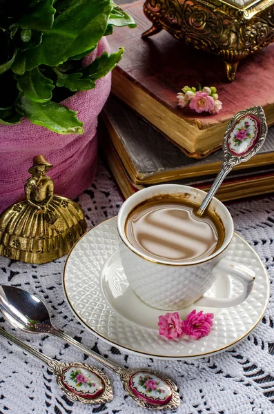 Hermosa naturaleza muerta vintage con flores, libros, una taza y una campana — Foto de Stock