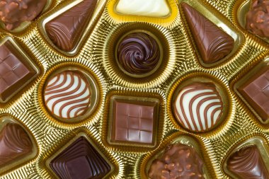 Ürün yelpazesine iyi çikolata şekerleme pralin, beyaz, koyu ve sütlü çikolata altın kutusunda. Pastane için ürün kavramı. Üstten Görünüm