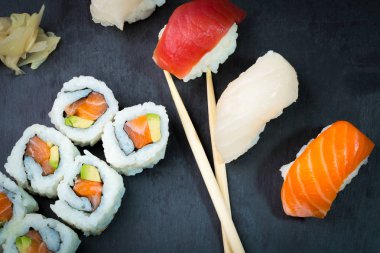 Suşi ve Sashimi rulo üzerinde siyah bir taş slatter. Taze yapılmış suşi somon, karides, wasabi ve zencefil ile ayarlayın. Geleneksel Japon mutfağı