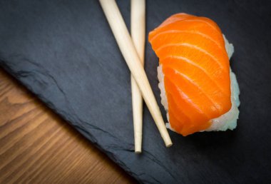 Suşi ve Sashimi rulo üzerinde siyah bir taş slatter. Taze yapılmış suşi somon, karides, wasabi ve zencefil ile ayarlayın. Geleneksel Japon mutfağı
