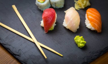 Suşi ve Sashimi rulo üzerinde siyah bir taş slatter. Taze yapılmış suşi somon, karides, wasabi ve zencefil ile ayarlayın. Geleneksel Japon mutfağı