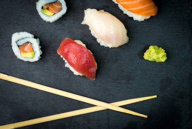 Suşi ve Sashimi rulo üzerinde siyah bir taş slatter. Taze yapılmış suşi somon, karides, wasabi ve zencefil ile ayarlayın. Geleneksel Japon mutfağı