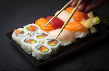Üzerinde siyah bir taş slatter çubuk çekme suşi ve Sashimi kullanarak ele alır. Taze yapılmış suşi somon, karides, wasabi ve zencefil ile ayarlayın. Geleneksel Japon mutfağı