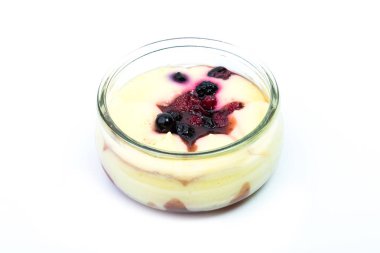 Chantily ile böğürtlen, ahududu ve beyaz bir arka plan üzerinde bir cam bardak yaban mersini taze krema