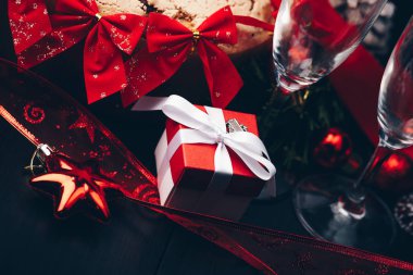 Noel ve yeni yıl. Şampanya gözlük mumlar, panettone ve kırmızı saten fiyonklu hediye paketi. Boşluk. Festival kavramı