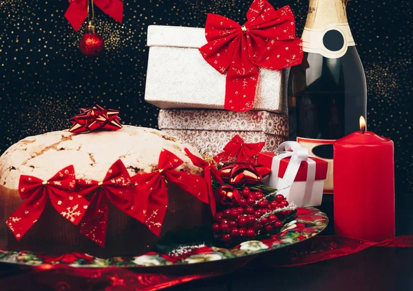 圣诞节或新的一年。在用蜡烛、 潘妮托妮和礼品红缎蝴蝶结眼镜香槟. — 图库照片