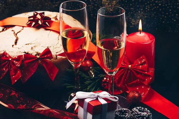 圣诞节或新的一年。在用蜡烛、 潘妮托妮和礼品红缎蝴蝶结眼镜的香槟。副本-空间。节日的概念 — 图库照片