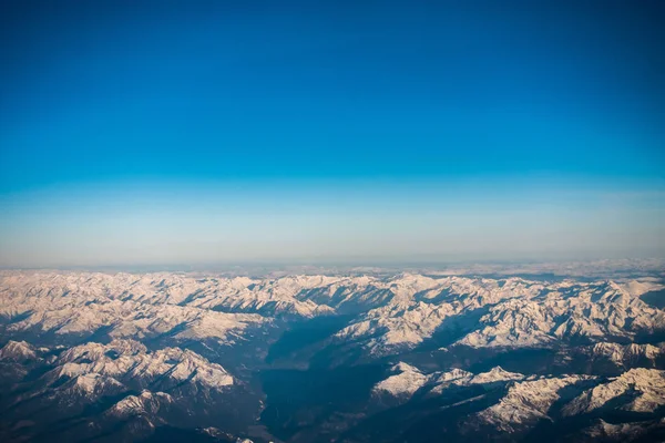 透过窗口飞机飞行的雪覆盖着蔚蓝的天空没有云意大利和 Osterreich 阿尔卑斯山 — 图库照片