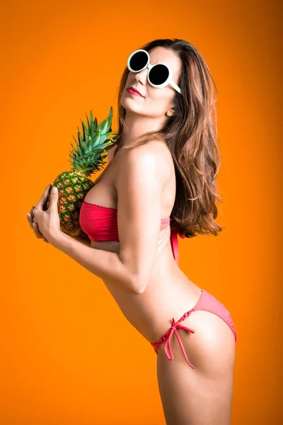 手に新鮮なパイナップルと赤いビキニの白いサングラス若い健康的な美しい女性の肖像画. — ストック写真