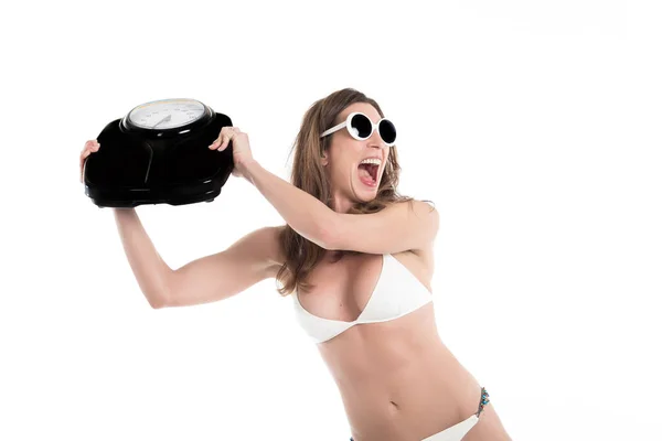Mujer joven en bikini blanco furioso lanzar escala de peso. Ajuste y concepto saludable. Aislado sobre fondo blanco —  Fotos de Stock