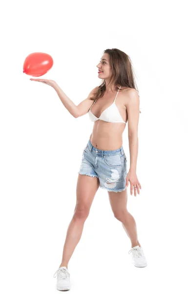 Piękna młoda brunetka Kobieta w białym bikini, grając z czerwonym sercem kształt balon — Zdjęcie stockowe