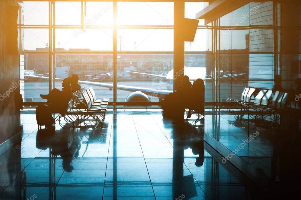 Silhouette of a unrecognizable travelers with backpack in international airport waiting lounge hall.  