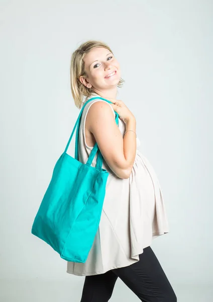 Linda jovem mulher grávida loira feliz com sacos de compras posando. Gravidez, maternidade, venda, pessoas e conceito de expectativa. Isolado em segundo plano . — Fotografia de Stock