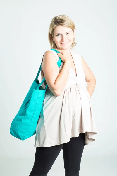 Piękny szczęśliwy młody blond kobieta w ciąży z torby na zakupy pozowanie. Ciąża, macierzyństwo, sprzedaż, ludzi i oczekiwanie koncepcja. Na białym tle na tle. — Zdjęcie stockowe