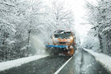 Kar temizleme aracı servis aracı ve buzlanma kış günü fırtınalı karda önlemek için tuz yol yüzeyinde yayılması tuzlama önden görünümü. 