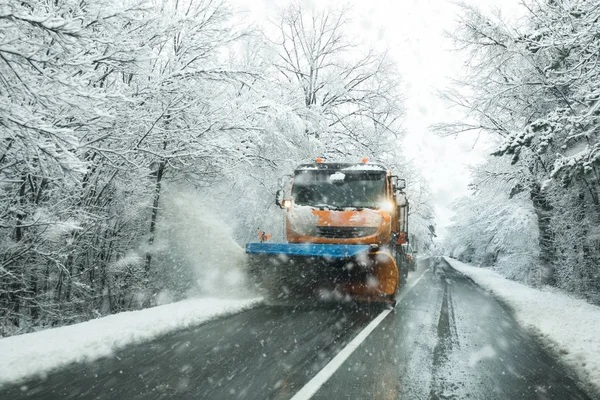 Kar temizleme aracı servis aracı ve buzlanma kış günü fırtınalı karda önlemek için tuz yol yüzeyinde yayılması tuzlama önden görünümü. 