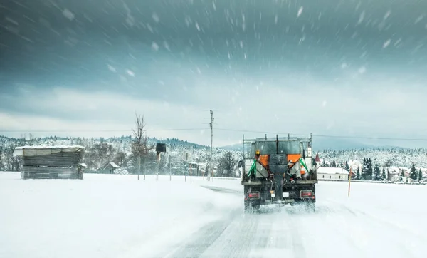 Winter service truck or gritter spreading salt on the road surface to prevent icing in stormy snow winter day.