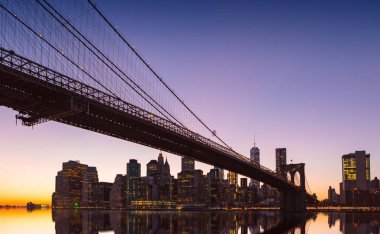 Manhattan'ın ünlü Brooklyn Köprüsü batımında ile New York City panoramik manzaralı.