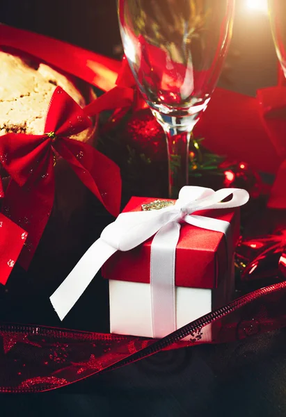 圣诞节或新年。香槟在眼镜与蜡烛, panettone 和礼物与红色缎弓。复制空间。假日概念 — 图库照片