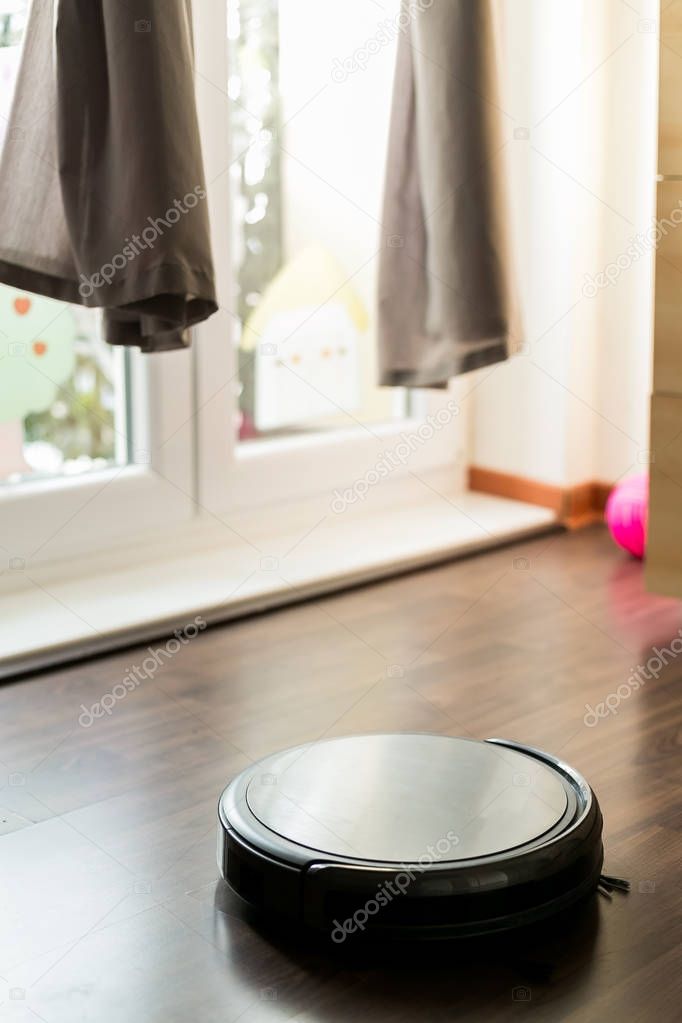 Robotic drone vacuum cleaner on laminate wood floor smart cleaning technology. 