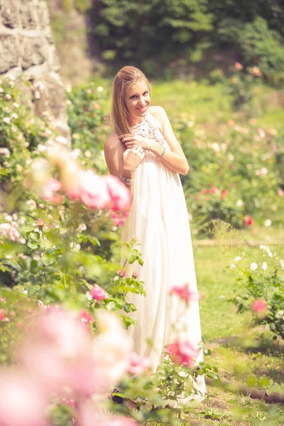 Uśmiechnięta Blondynka Spacerująca Ogrodzie Kwitnącymi Krzakami Psiej Róży — Zdjęcie stockowe