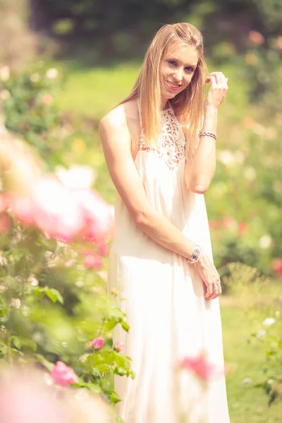 Mujer Rubia Sonriente Vestido Caminando Jardín Floreciente Fondo Borroso —  Fotos de Stock