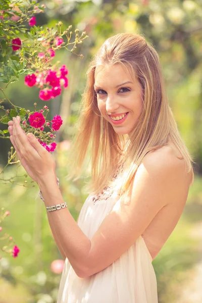Glimlachende Blonde Vrouw Poseren Buurt Van Hond Roos Bush — Stockfoto