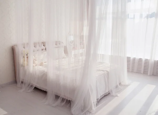 Υπνοδωμάτιο με ένα λευκό κρεβάτι, μεγάλο καθρέφτη κοντά στο παράθυρο — Φωτογραφία Αρχείου