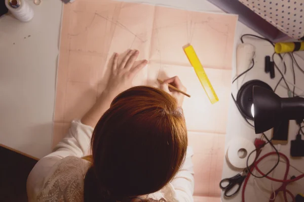 Швея рисует рисунок на графической бумаге в студии — стоковое фото