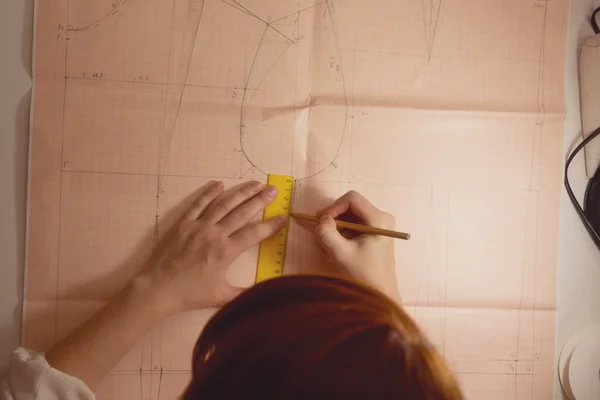 Näherin zeichnet Muster im Atelier auf Graphikpapier — Stockfoto
