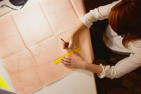 seamstress draws the pattern on graph paper in the studio