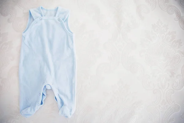 婴儿的衣服，白色的床上 — 图库照片