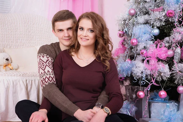 Młoda para szczęśliwy, obejmując w pobliżu obchodzi Boże Narodzenie drzewo — Zdjęcie stockowe